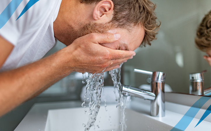 Man washing is face at sink