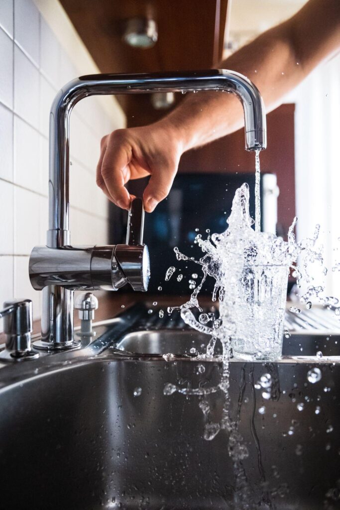 running-and-Splashing fresh water from kitchen faucet filling glass